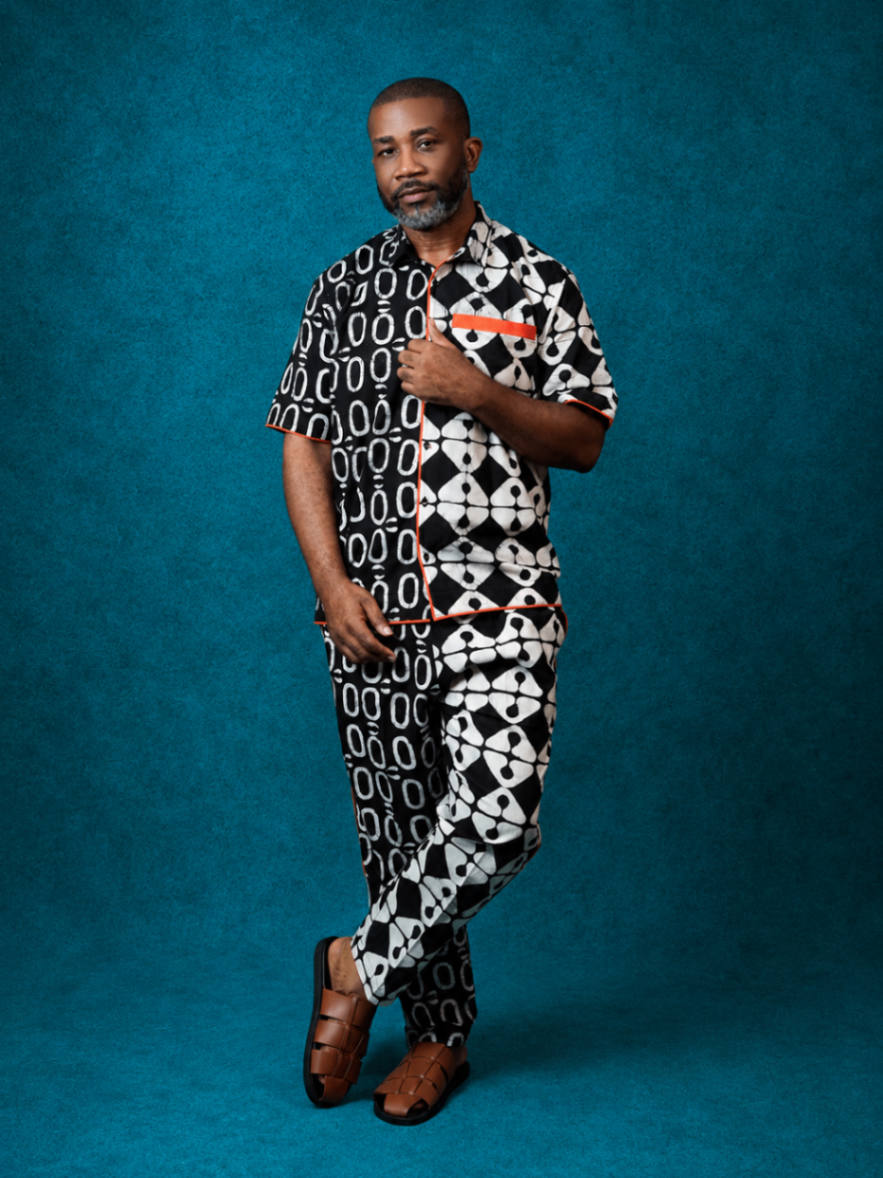 Model wearing an OBIDA half-and-half black-and-white short-sleeve set against a teal studio backdrop.