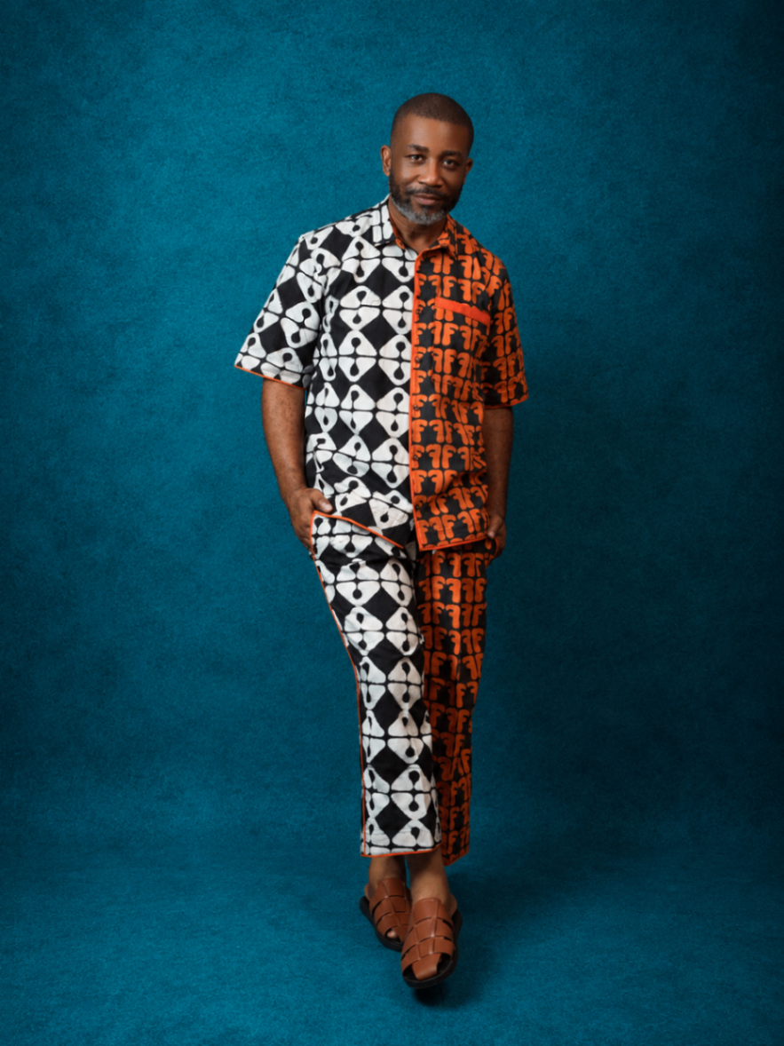 Model wearing an OBIDA black, white, and orange split-pattern set against a teal studio backdrop.