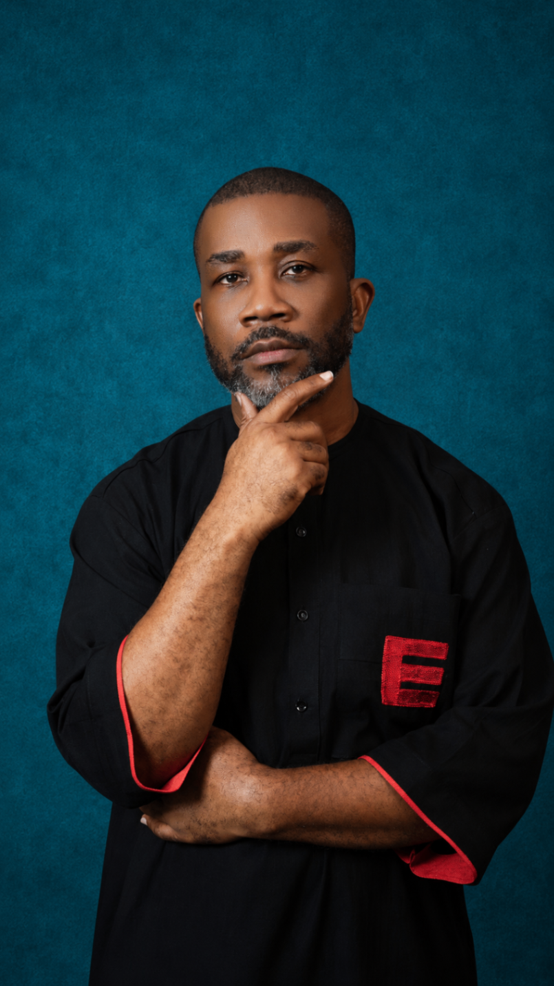 Portrait of a model wearing a black OBIDA kaftan top with red detailing against a teal studio backdrop.