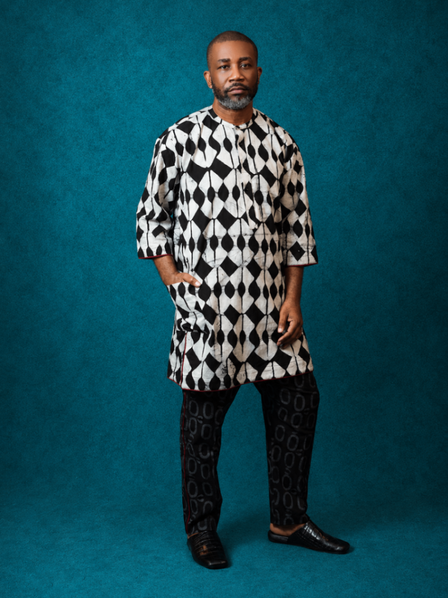 Model wearing an OBIDA black-and-white kaftan set against a teal studio backdrop.