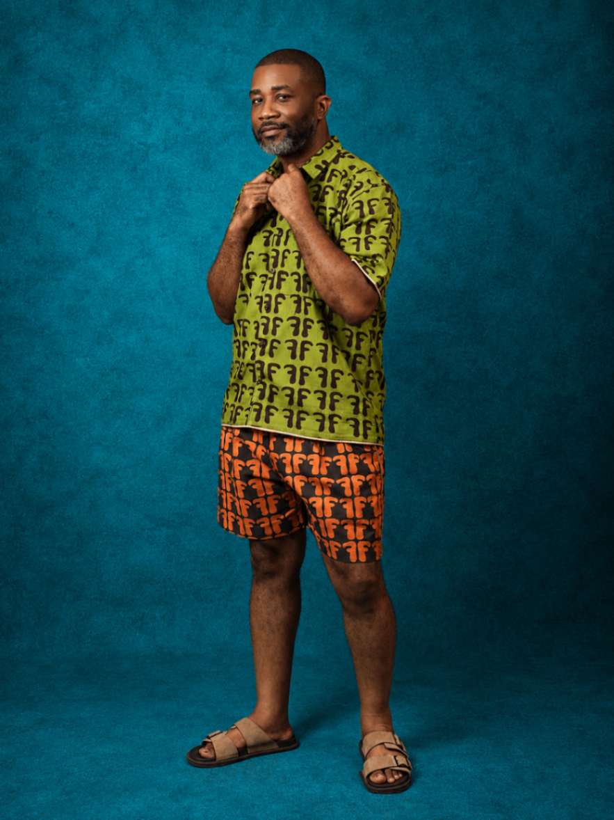 Model wearing an OBIDA green shirt and orange shorts set against a teal studio backdrop.