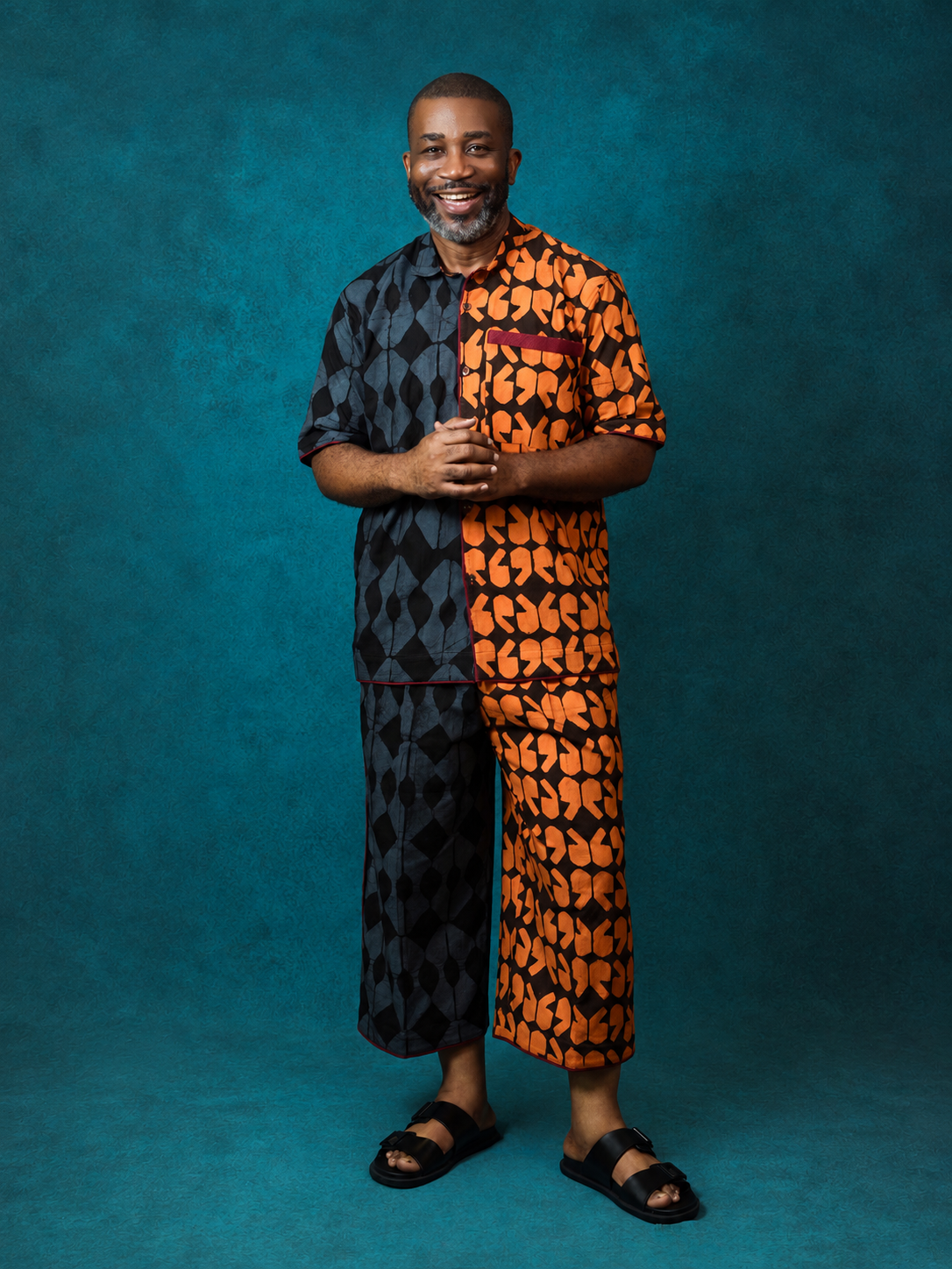 Model wearing an OBIDA contrast black and orange patterned short-sleeve set against a teal studio backdrop.
